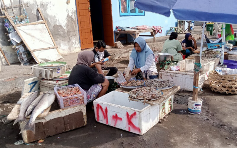 A woman selling shrimp at an outdoor market in Indonesia