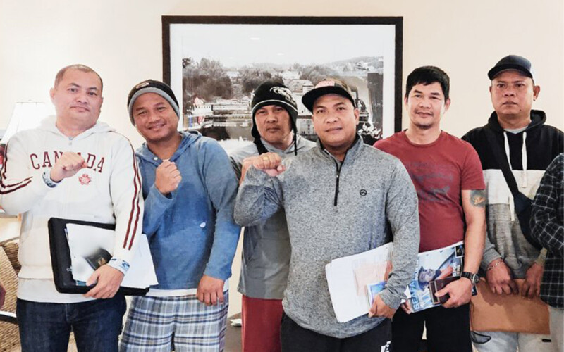 A group of six Filipino men in sweaters holding up their fists