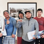 A group of six Filipino men in sweaters holding up their fists