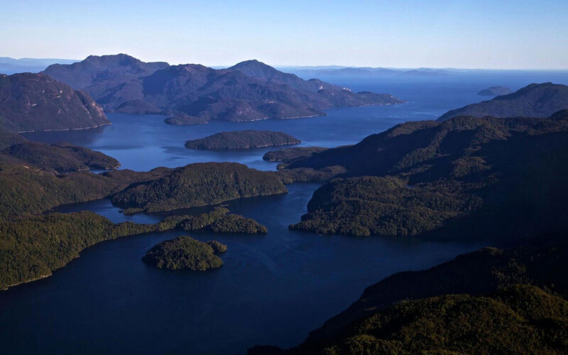 An aerial shot of Isla Magdalena National park in Chile showing deep blue water and rising green mountains