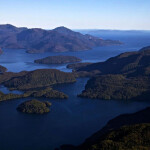 An aerial shot of Isla Magdalena National park in Chile showing deep blue water and rising green mountains