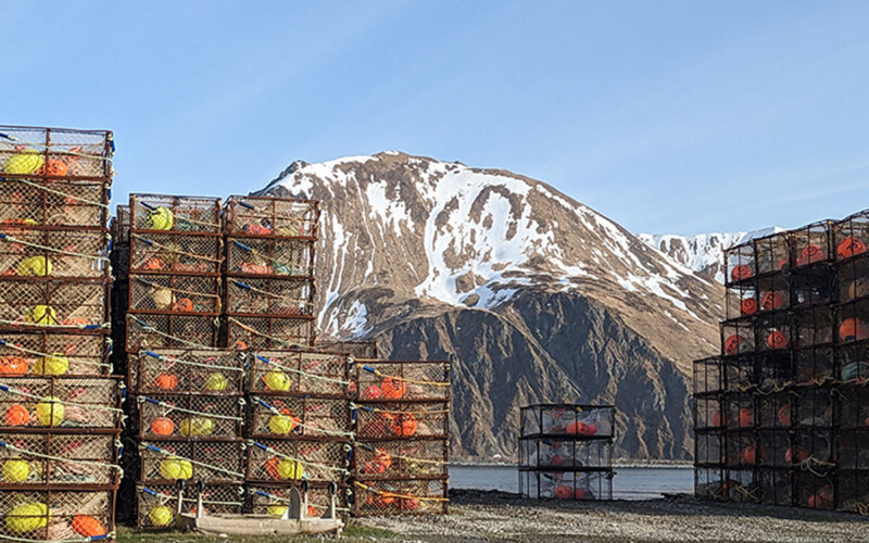 Crab pots on a dock, with an Alaskan mountain in the distance