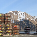 Crab pots on a dock, with an Alaskan mountain in the distance