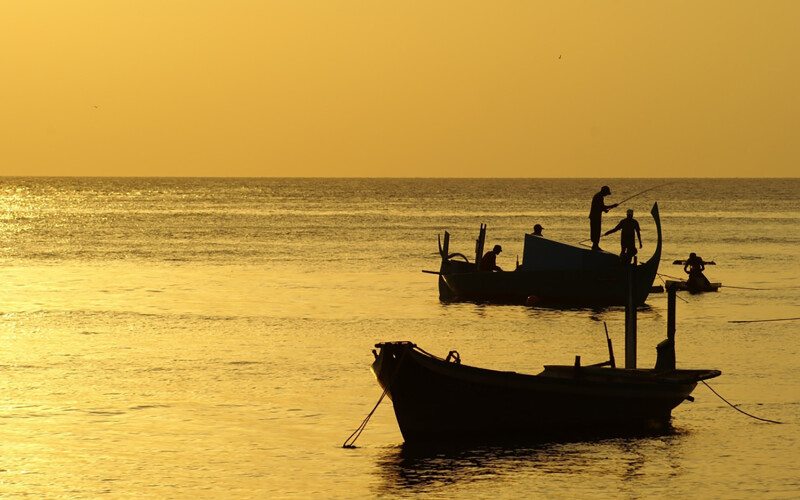 A photo of fishing boats in the Maldives at sunset