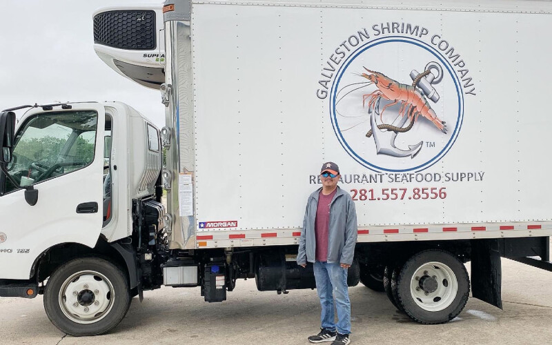 A man standing in front of a Galveston Shrimp Company truck