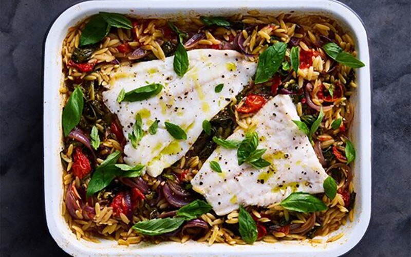 A photo of a dish containing baked Norwegian cod and cherry tomato orzo