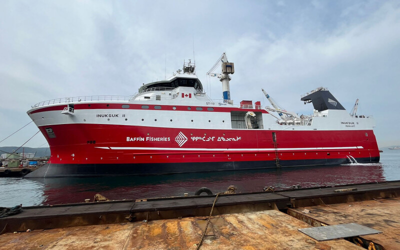 A photo of the red-and white colored Inuksuk II, an 80-meter long fishing vessel, at a dock.