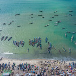 An aerial photo of artisanal fishing boats lined up on the coast of Tanji, a Gambian fishing village