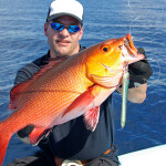 A photo of a fisher holding a red snapper.