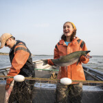 Emily Taylor, a fifth-generation native Alaska salmon fisher, holding a Bristol Bay sockeye salmon in a fishing boat