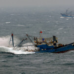 A fishing trawler pounding through waves in the South China Sea