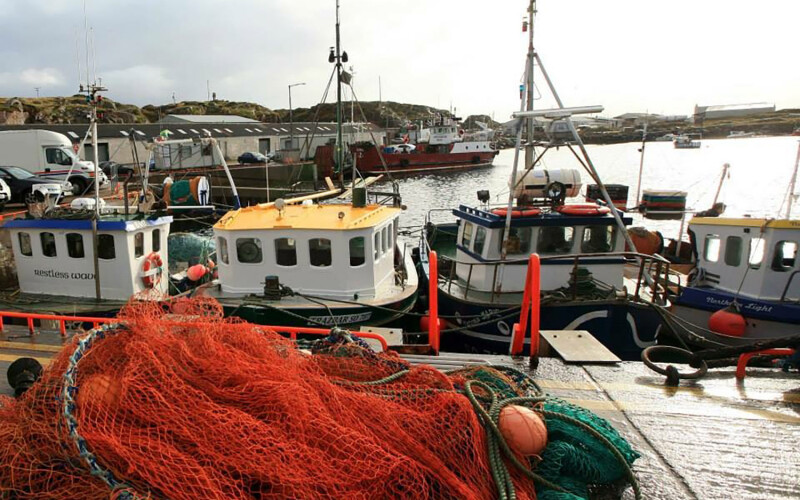 Irish inshore fishing boats lined up at a dock with netting piled up in the foreground