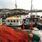 Irish inshore fishing boats lined up at a dock with netting piled up in the foreground