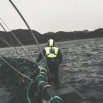 A Grieg Seafood farmer tending to a net pen on the open ocean