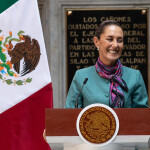 Mexican President Claudia Sheinbaum at a podium in front of the Mexican flag