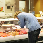 A man bending over to look at fresh seafood inside a case.