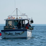 Lobstermen in Nova Scotia pulling in a lobster trap.