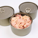 Three unbranded cans of tuna, with one can open