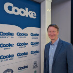 Cooke Vice President of Public Relations Joel Richardson standing next to Cooke logos at its booth at the 2025 Seafood Expo North America