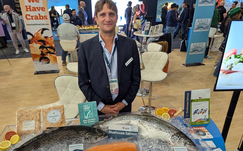 Atlantic Sapphire Chief Sales and Marketing Officer Damien Claire standing behind examples of the company's bluehouse salmon