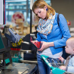 A woman looking in her wallet at a checkout counter at a grocery store