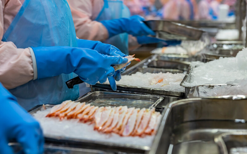 Workers wearing protective gear process shrimp in a Vietnam-based facility