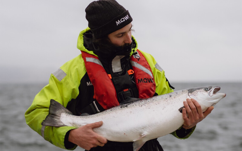 A Mowi employee holding a farmed salmon