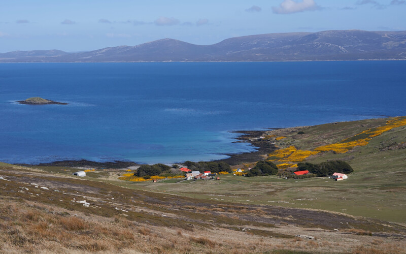An aerial shot of the water off the Falkland Islands with a farm in the foreground