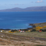 An aerial shot of the water off the Falkland Islands with a farm in the foreground