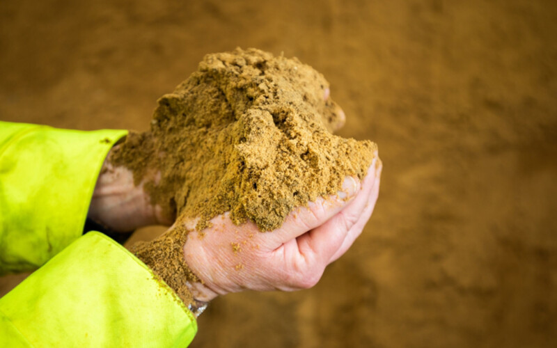 A person holding a handful of fishmeal