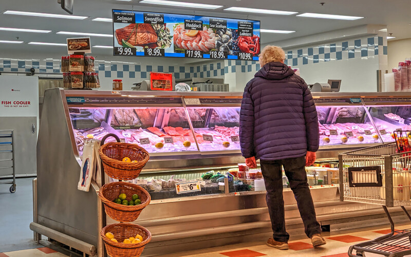 A woman standing at a seafood counter in a grocery store
