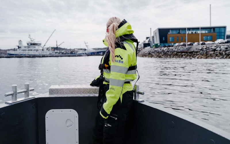 A SalMar employee on a boat facing away from the camera on a boat