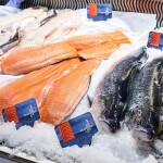 A seafood counter featuring salmon fillets with Norwegian flag labels