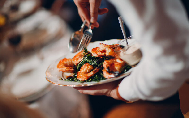 A waiter serving a shrimp dish