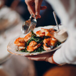A waiter serving a shrimp dish