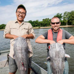 Two fishermen holding large blue catfish