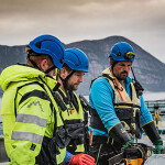 Three Kvarøy Fiskeoppdrett employees standing on a net pen