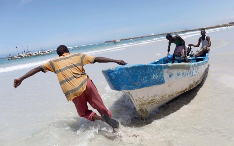 Fishermen pulling their boat toward the water off of Mogadishu, Somalia