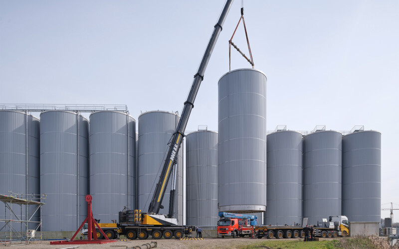 A crane installing a large storage tank