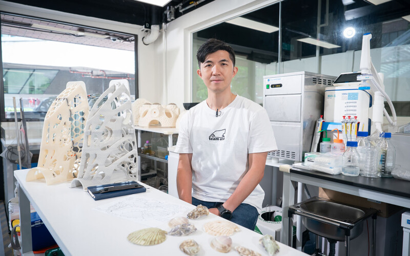 Dean Chan in a laboratory posing next to a Reef of Hope