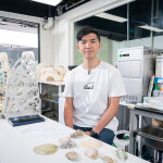 Dean Chan in a laboratory posing next to a Reef of Hope