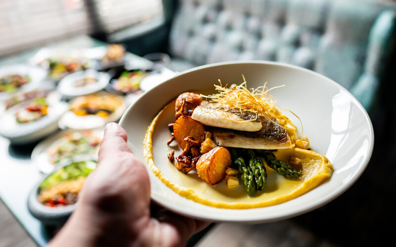 A person holding out a seafood dish at a restaurant