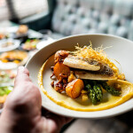 A person holding out a seafood dish at a restaurant