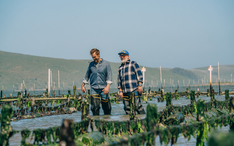 Barton Seaver and Andrew Zimmern walking at an aquaculture operation