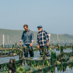 Barton Seaver and Andrew Zimmern walking at an aquaculture operation