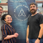 Staff at Atlantic Fish Co posing before a banner