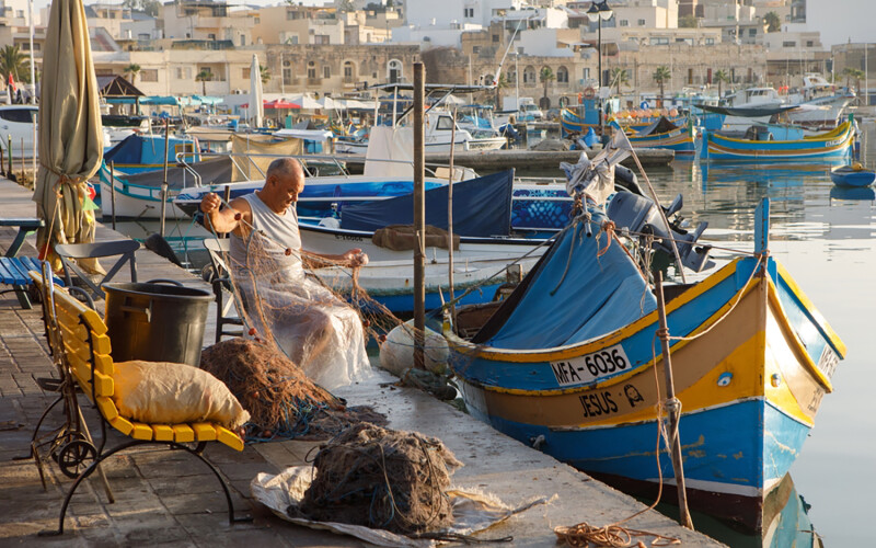 A Maltese fisherman untangling his nets