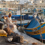 A Maltese fisherman untangling his nets