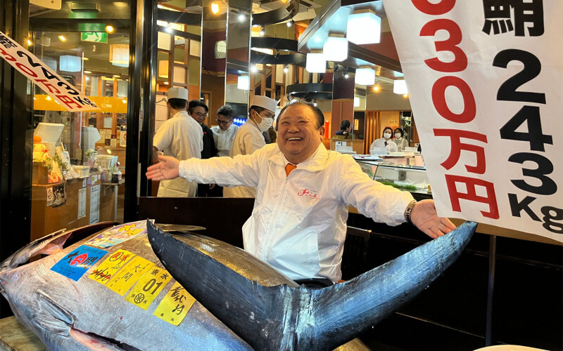 Sushizanmai Head Kiyoshi Kimura spreading his arms over the large bluefin tuna he won at auction