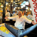 Sushizanmai Head Kiyoshi Kimura spreading his arms over the large bluefin tuna he won at auction